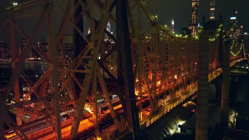 Terrific Queensboro Bridge with busy traffic at nighttime. Drone footage up along the bridge.