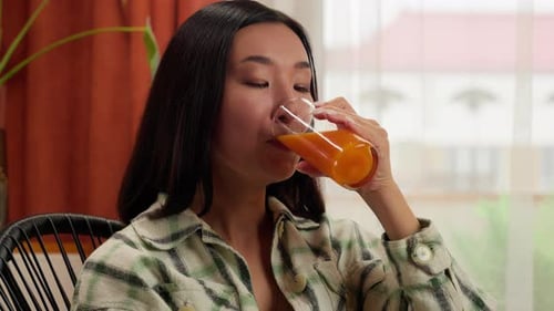 Woman Drinking Juice and Using Laptop at Home