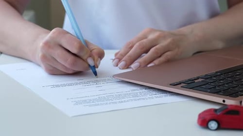 Woman Signing Loan Paper Document with Red Toy Car on Foreground