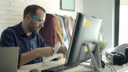 Man Working at Desk Looks at Documents