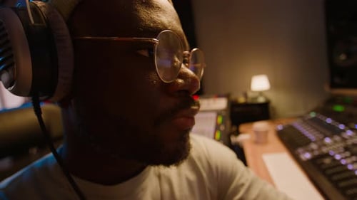Man in Studio with Soundboard, Headphones, and Glasses