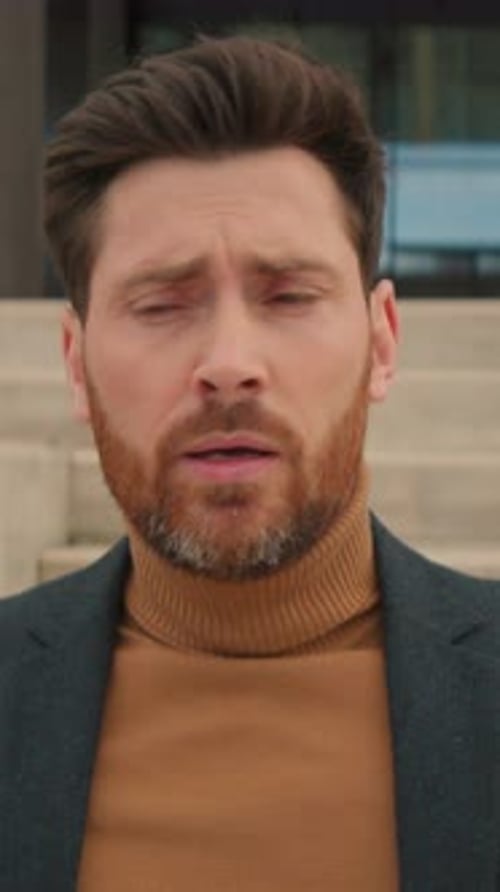 Footage of Depressed Young Beared Man Holding Box with Personal Stuff Standing Near Office Building