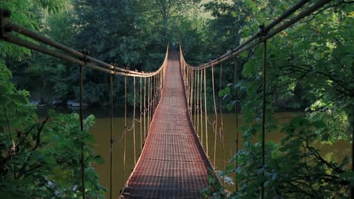 Walk along the iron bridge that hangs over the river. The iron suspension bridge wobbles.