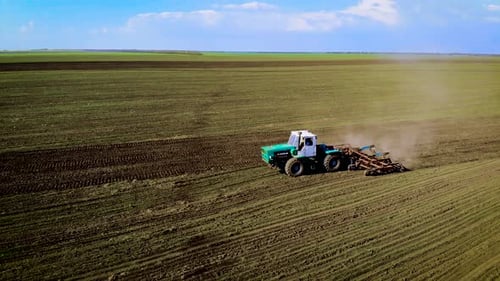 Aerial View on Large Vintage Tractor Cultivates Field and Prepares Dry Soil for Sowing Crops Under
