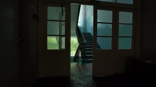 Light Streaming Through Open Doors Illuminates a Shadowy Hallway and Staircase in an Empty School on