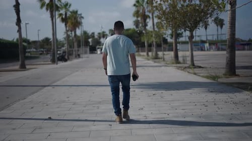 Young Adult Walking Away on Tropical Sidewalk