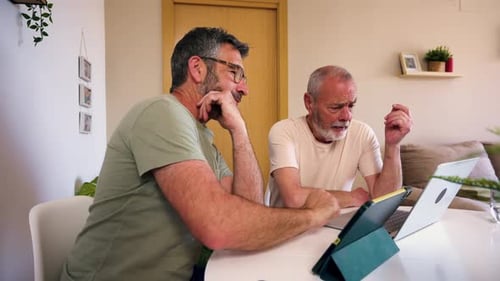 Two Men Discussing Information on Laptop at Table