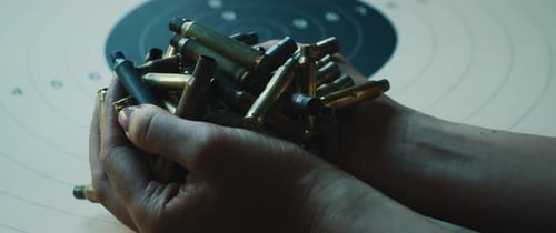 Woman Holds Spent Bullet Casings Over Target
