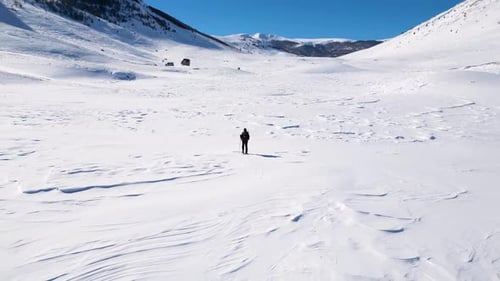 Vista aérea en Zumbido de un excursionista solitario caminando por las montañas durante el invierno.