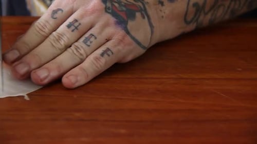 Male tattoed hands slicing raw white fish with a knife on a wooden cutting board in slow motion with
