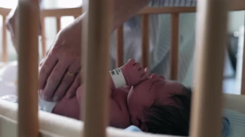 Changing Diaper of Newborn Infant in Hospital Crib