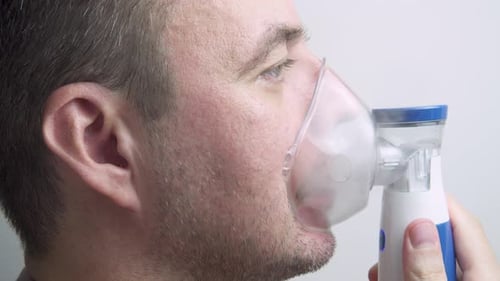 Sick man is using nebulizer at home