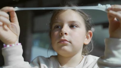 Girl Stretches Clear Putty Between Her Hands