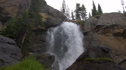 Big flowing waterfall with mist and snowy conditions in the rocky mountains (4k 60fps SLOW MOTION)