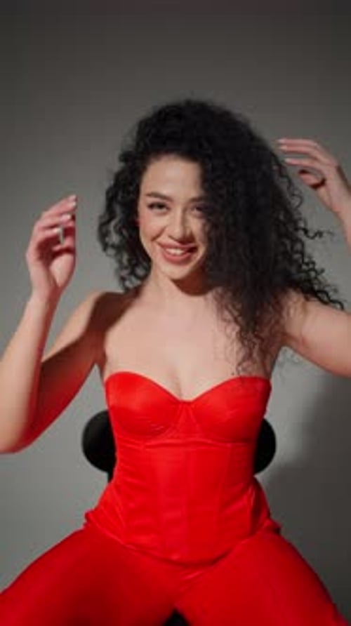 Radiant Smile in Red Curlyhaired Woman Laughing in a Red Outfit