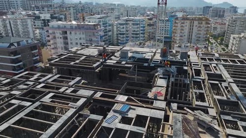 Turmdrehkran hebt Platten auf einer Baustelle in der Nähe der Mittelmeerküste mit sichtbaren Arbeitern