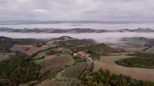 Aerial view of foggy sunrise over villa in Tuscany, Italy.