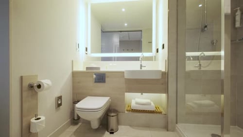 Slider-Aufnahme eines modernen gefliesten Badezimmers mit Dusche in einem modernen Wohn- und Immobilieninterieur. Weitwinkelaufnahme.