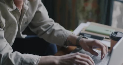 Young Adult Typing on Laptop at Desk