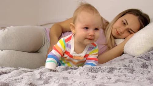 Crawling Infant with Sleeping Woman Lying on Bed