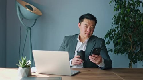 Relaxed Male Making Sip of Hot Beverage While Lounging at Workspace in Cabinet