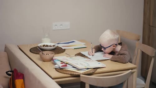 Child Drawing in a Notebook at Table