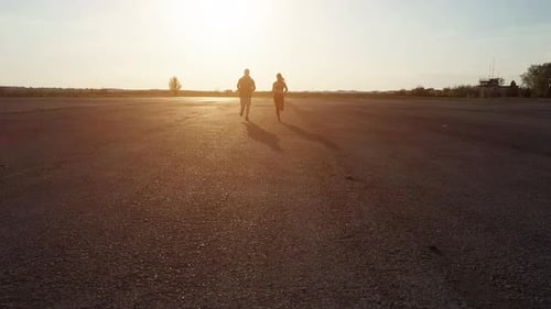 Hombre en ropa blanca y negra corriendo con una mujer en ropa deportiva al aire libre por la noche