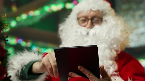 Santa Claus Uses Tablet at Christmas Indoors