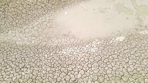 Top down aerial descending view of brown dry mudcracks in earth