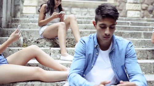 Young Adults Using Technology on Stone Staircase