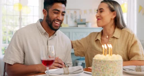 Couple, birthday and cake with kiss, blowing candles and hug, smile and clapping at a party in home