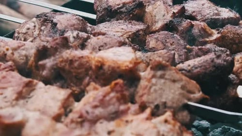 Shish Kebabs on Skewers are Cooked on the Grill Outdoors