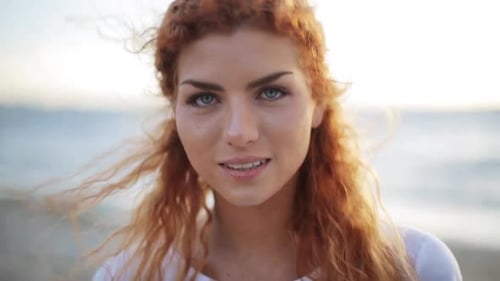 Happy young redhead woman laughing freely on a sunny beach