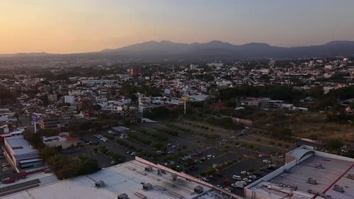 Toma aérea de la ciudad de Cuernavaca al atardecer, mostrando un Walmart y sus alrededores
