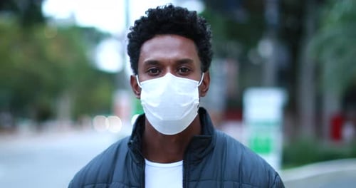 Confident African American wearing face mask walking in city downtown