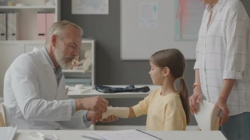 Doctor Applies Bandage to Child's Wrist in Clinic