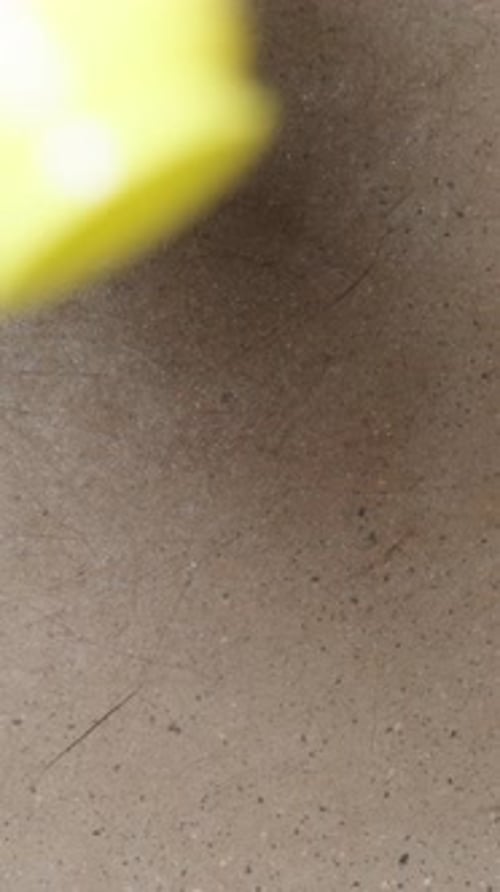 Vertical video. Top view, oil is poured from the bottle onto the skillet, in slow motion.