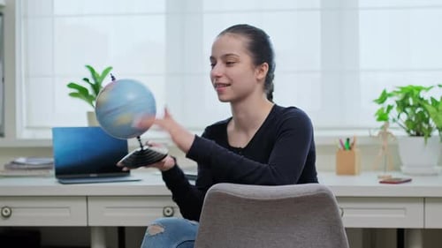 Teenager-Mädchen hat Spaß daran, den Globus zu drehen und mit dem Finger auf den Globus zu zeigen