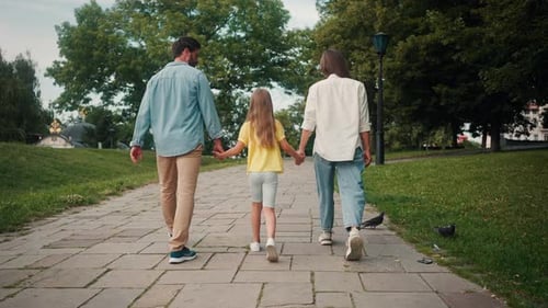 Family with Daughter Walks on Green Park Path Holding Hands