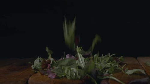 Fresh organic colorful greens lettuce falling on wooden table, close-up view