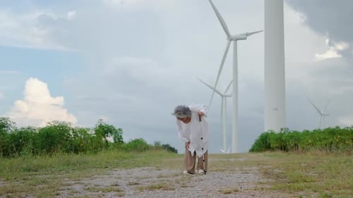 Senior asian woman walking in the farm in the background are windmills had sudden knee pain