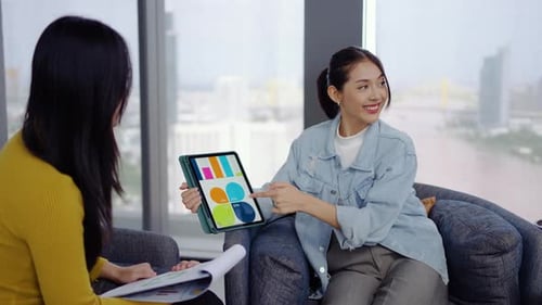 Business Women Discussing Data on a Tablet in Office