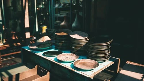 Stacked Metallic Plates Displayed on a Wooden Table in a Market Setting