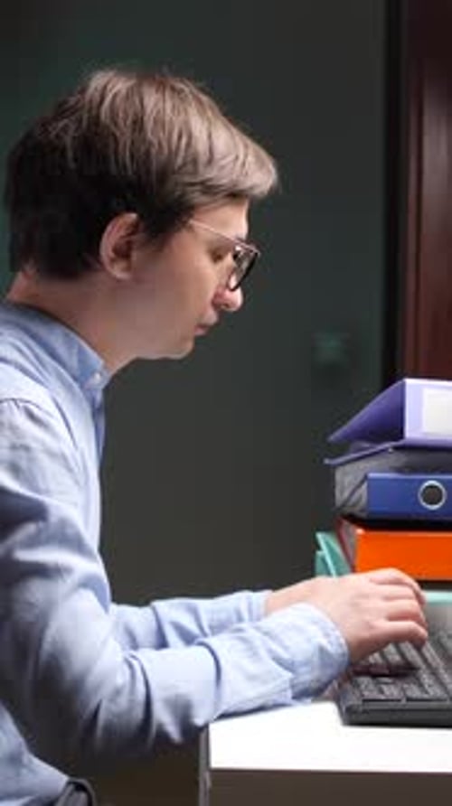 Vertikale Video-Nahaufnahme: Büroangestellter analysiert nachts Diagramme auf dem Computerbildschirm