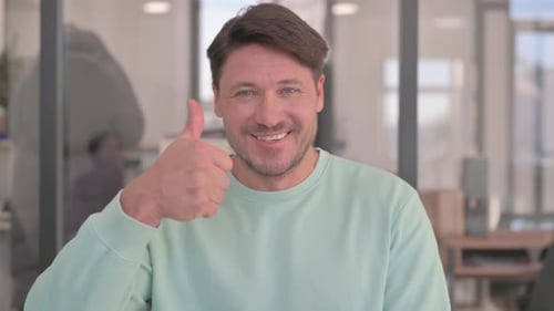 Smiling Man Gives Thumbs Up in Bright Office
