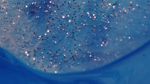 Sparkly Glitter Swirling on Bright Blue Background