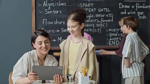 Lehrer erklärt Schülern mit Tablet die Robotikstunde