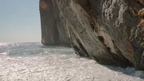 Sunlit Cliffside and Ocean Waves Create a Majestic Coastal Scene with Sunlight Reflecting on the