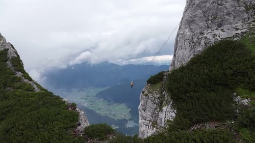Aerial View of a Highliner Walking a Slackline Between Mountain Cliffs