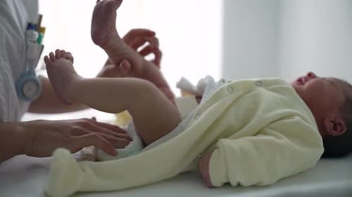 Nurse Changes Diaper of Newborn Baby on Table
